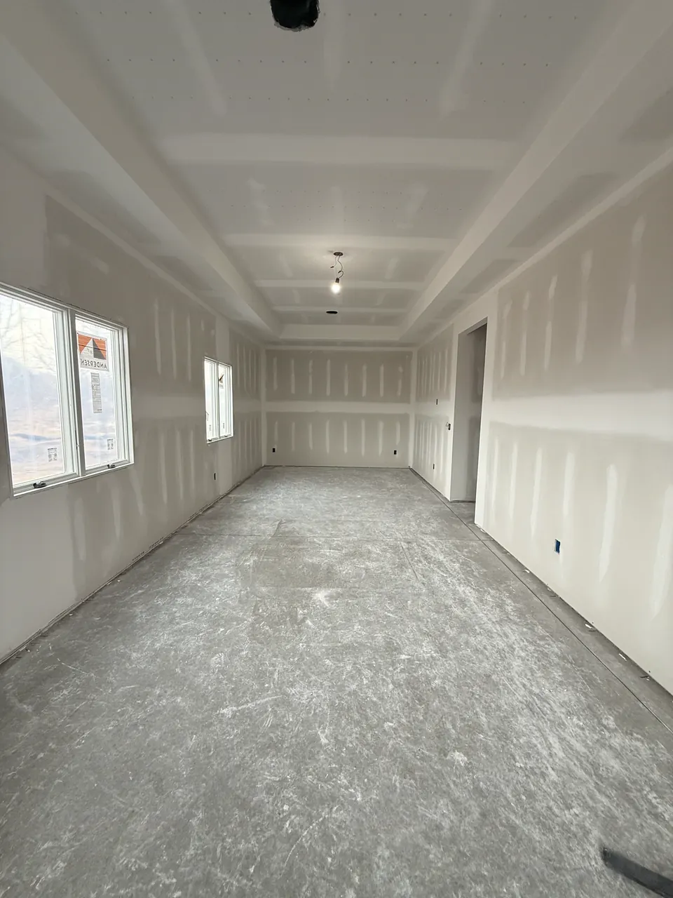 Long room with coated drywall joints and a ceiling light