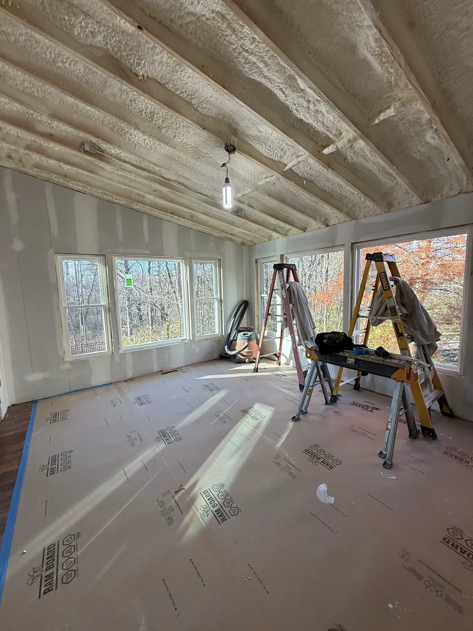 Room with coated drywall seams, ladders, and exposed ceiling framing