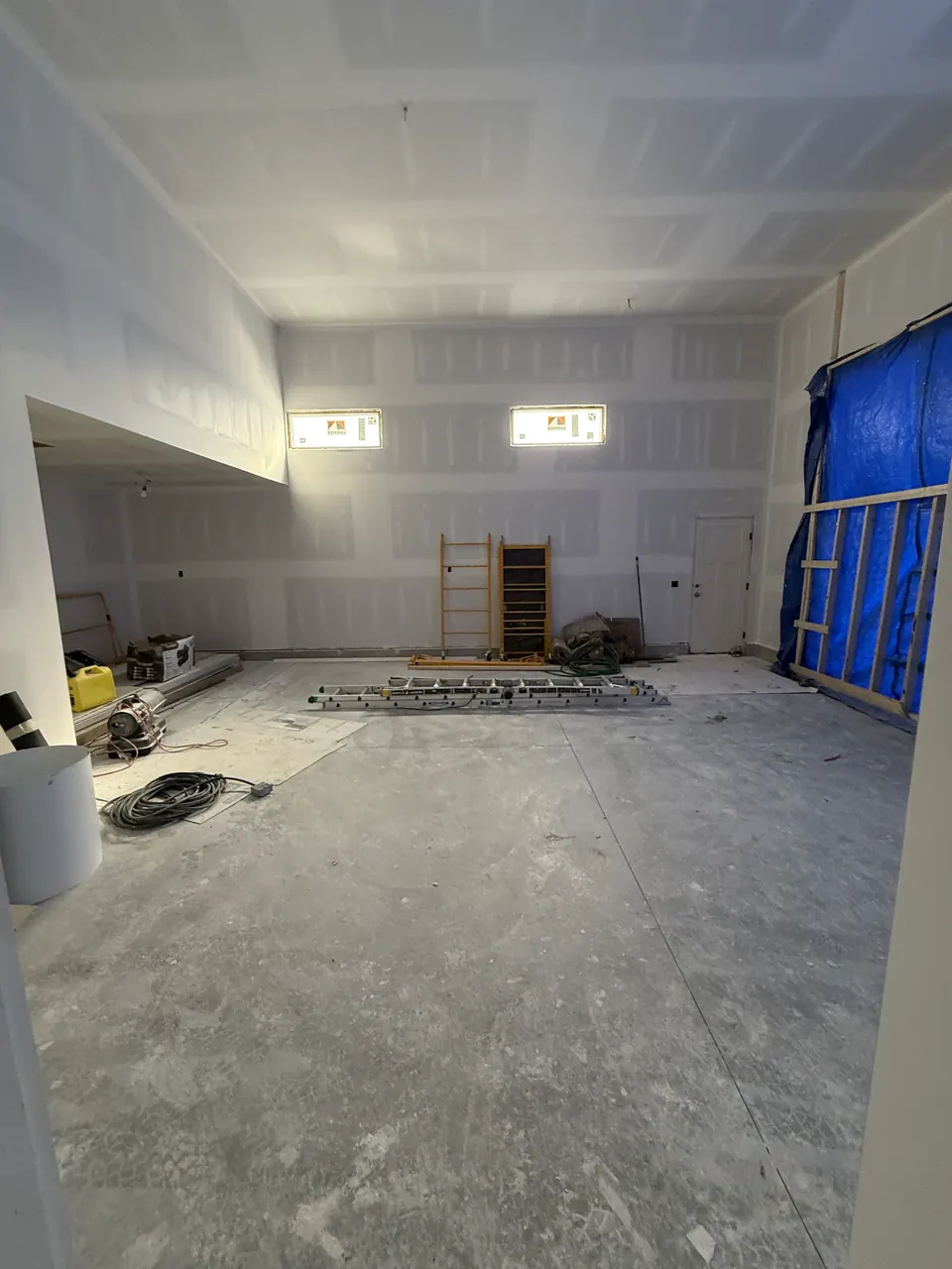 Tall room with coated drywall seams and a protected opening
