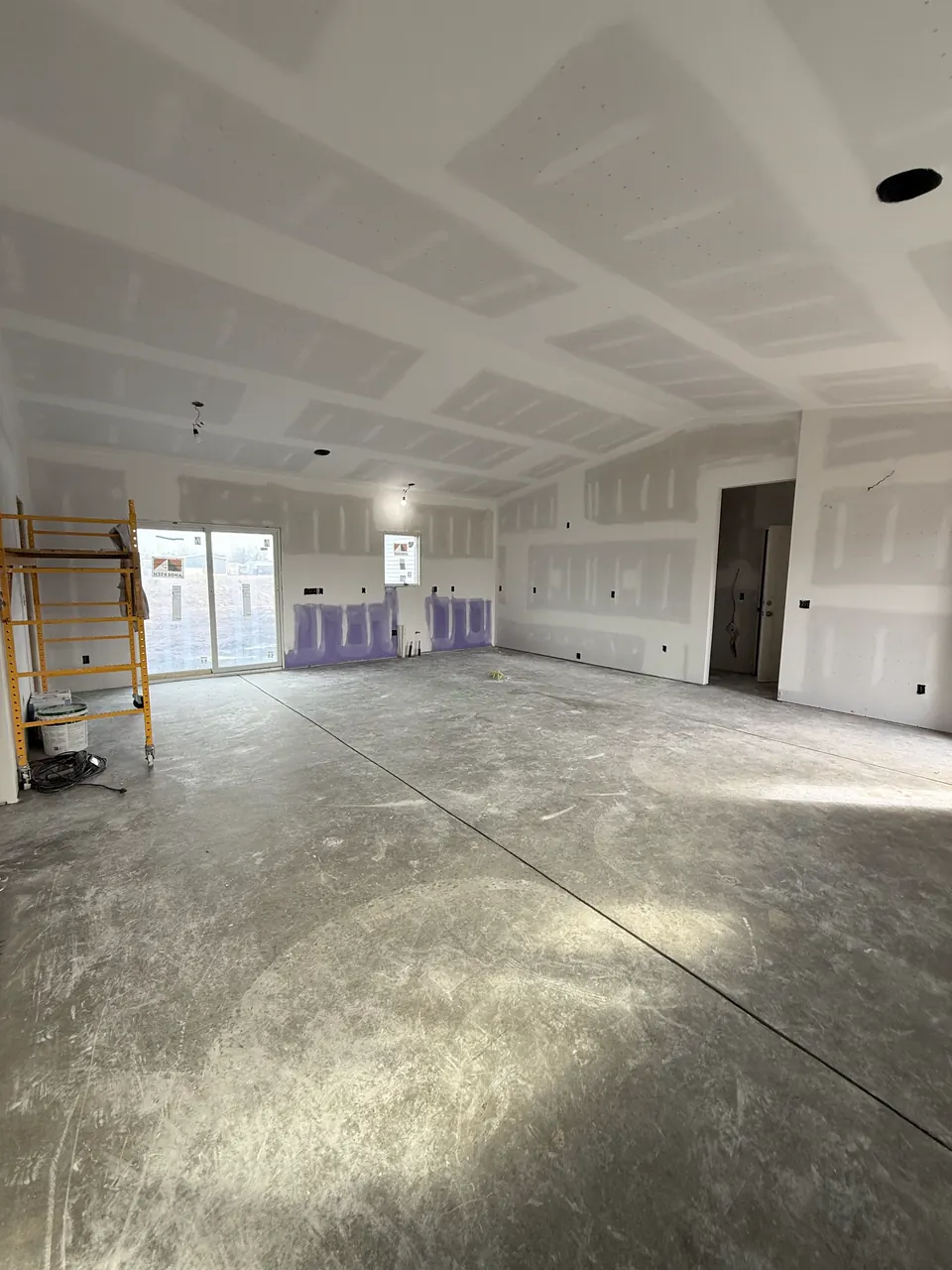 Wide room with coated drywall seams and a rolling scaffold
